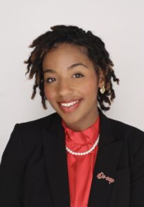 professional head shot of Channing-Jaye in black blazer and red blouse and pearl accessories.